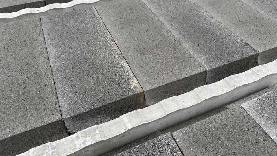 Close-up van betonnen renovatievloeren met treden met een gestructureerd oppervlak en witgeschilderde randen, die in een diagonaal patroon zijn aangelegd.