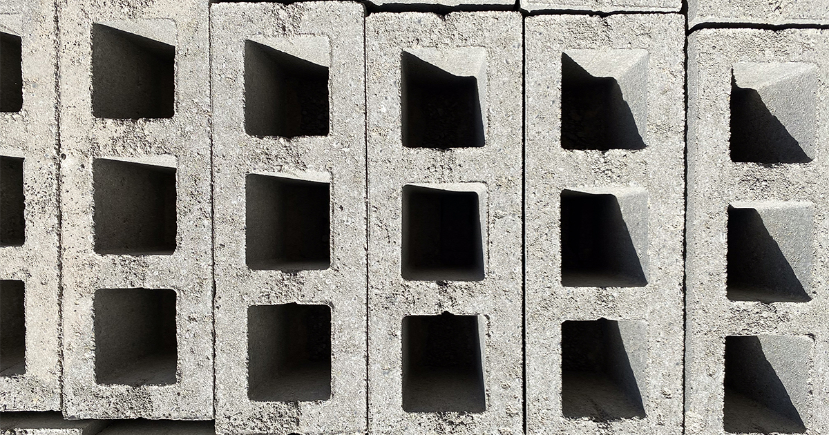 Gestapelde Carbstone-blokken met vierkante holtes gerangschikt in een muurpatroon.