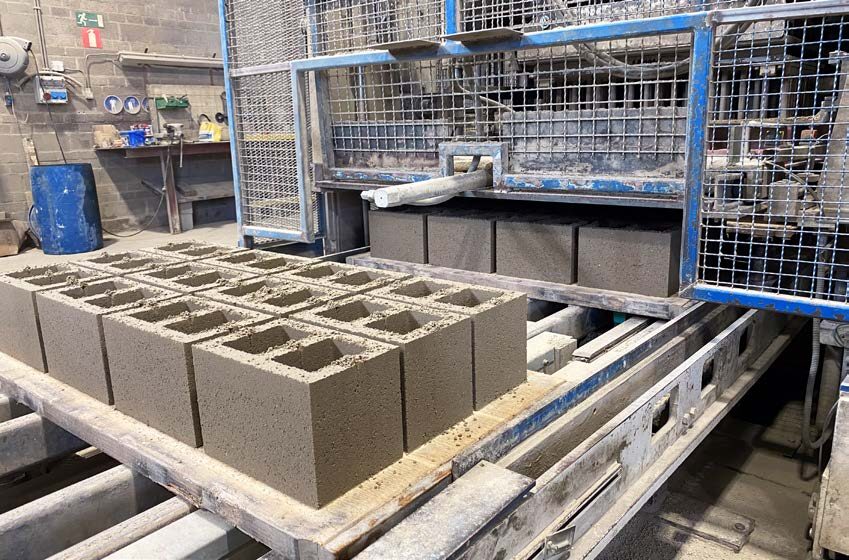 Cementvrije bouwsteenblokken worden gevormd en uitgelijnd op een productielijn, waarmee de toewijding van de industriële faciliteit aan koolstofnegatieve oplossingen zoals Carbstone wordt getoond.